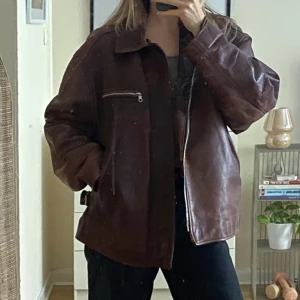 Bikerjacka läder - Oversize brun läderjacka med åtdragbara spännen i sidorna så du kan välja en mer boxig eller rak form. Innerficka och ytterfickor i sidorna. Ganska stor på mig som är S/M så nice till hösten/vintern med plats för tröja under om du är samma storlek som mig