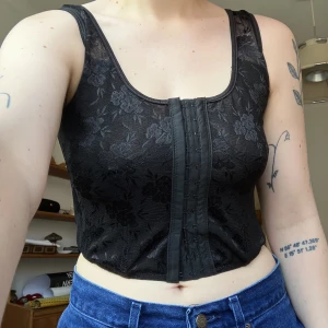 Korsettopp från Dollskill  - Fin svart korsettopp med blommönster. Sitter inte riktigt rätt på mig och används inte längre. Stängs med hyskor fram. Skriv vid frågor :)