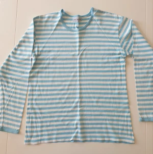 Marimekko tröja - Långärmad marimekko tröja med vita och ljusblå-turkosa ränder. Tröjan har tecken på användning. Kan skicka fler bilder och tänka mig sänka priset. Hör av dig vid intresse!