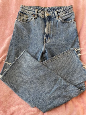 Monki Taiki strl 24 - Fina jeans från monki, högmidjade, snygg tvätt. Avklippta nertill. Innerbenslängd 73 cm, midjan rakt över 34 cm.  
