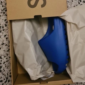 Yeezy slides Azure - Säljer mina yeezy slides helt nya från ADIDAS CONFIRMED storlek 42. Har box och kvitto