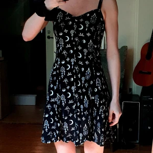 Svart kort klänning med olika symboler - Miniklämning med knäppning framtill. Div "spirituella" symboler såsom yin och yang, drömfångare, måne m.m. enligt bild.  Sparsamt använd. Från Monki 🤗