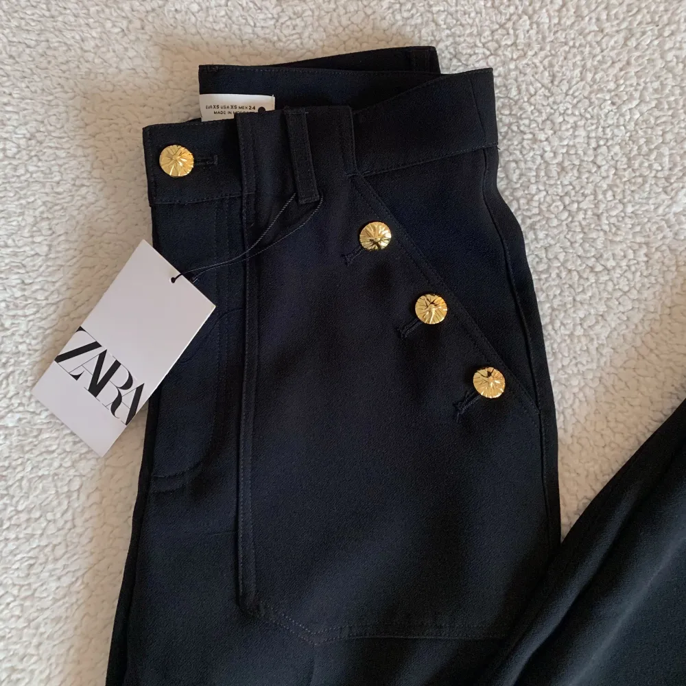 Svarta kostymbyxor med guldiga knappar frn ZARA. Hödmidjad modell med rak utsvängd passform. Aldrig använda. I nyskick, utan anmärkningar med tags kvar. Nypris 559. 🌻. Jeans & Byxor.
