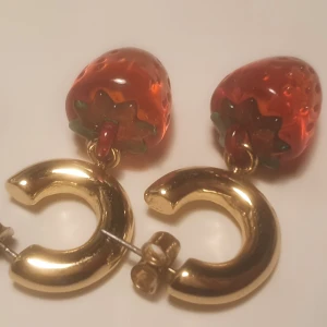 Jordgubbs örhängen  - Ett par gulliga jordgubbs örhängen som är köpta från Monki och anvånda typ en gång, har jätte fin färg och är gjord av glas. Frakt är 15 kr