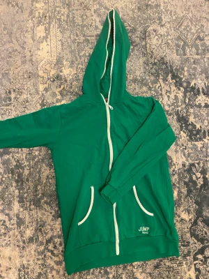 Grön zip up hoodie  - En grön zip up hoodie med vita detaljer, lite kortare model i armarna