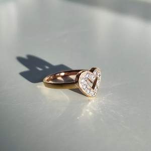 En festlig och glittrande ring med kristaller i ett hjärta! Färgen påminner mer om rosguld än vanlig guld. Ringen är hel och fin men har använts en del. Diameter innermått: 17,5 mm