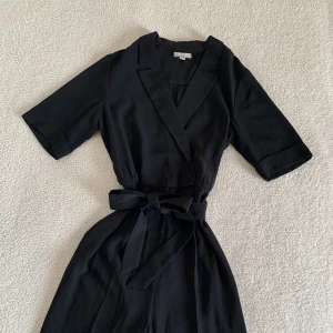 KOSTYM JUMPSUIT H&M - Så jädrans snygg jumpsuit ”kostym”-aktig från H&M. Omlott som stängs med enkel knapp. Knyts med rosett i midjan. Snygga och stiliga raka ben. 🌻 Aldrig använd, i nyskick utan anmärkningar. 🌻