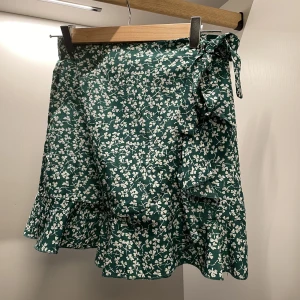 Grön kjol! - Fin sommar kjol med vita blommor, volang, knybar rosett och dragkedja i sidan. Knappt använd 🫶