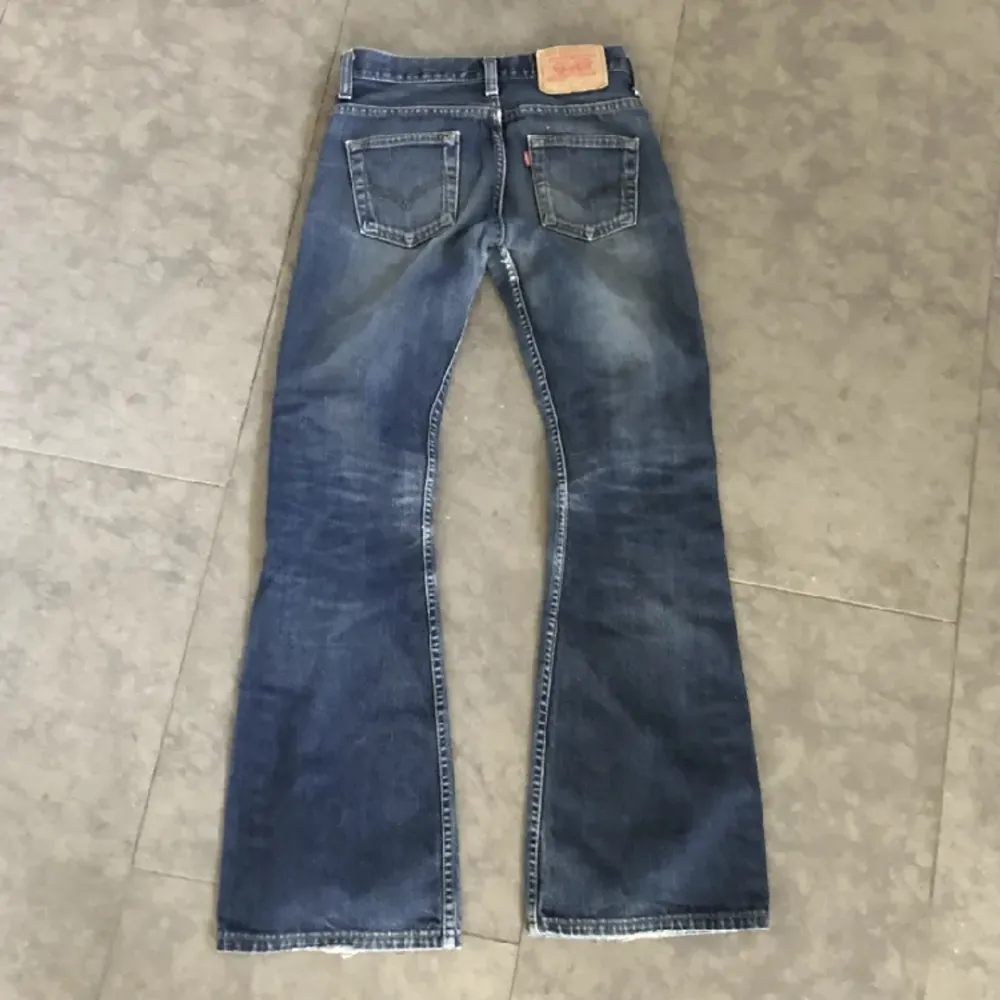 Mörkblå Levis utsvängda / bootcut jeans. Köpta second hand. Storlek 27. Innerbenslängd: 76 cm, midjemått rakt över: 35 cm. För små för mig :( . Jeans & Byxor.