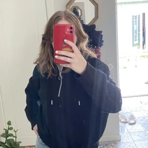 Svart hoodie - Svart hoodie med en silvrig dragkedja som går ungefär halvvägs ned på plagget. Både varm och mysig. 