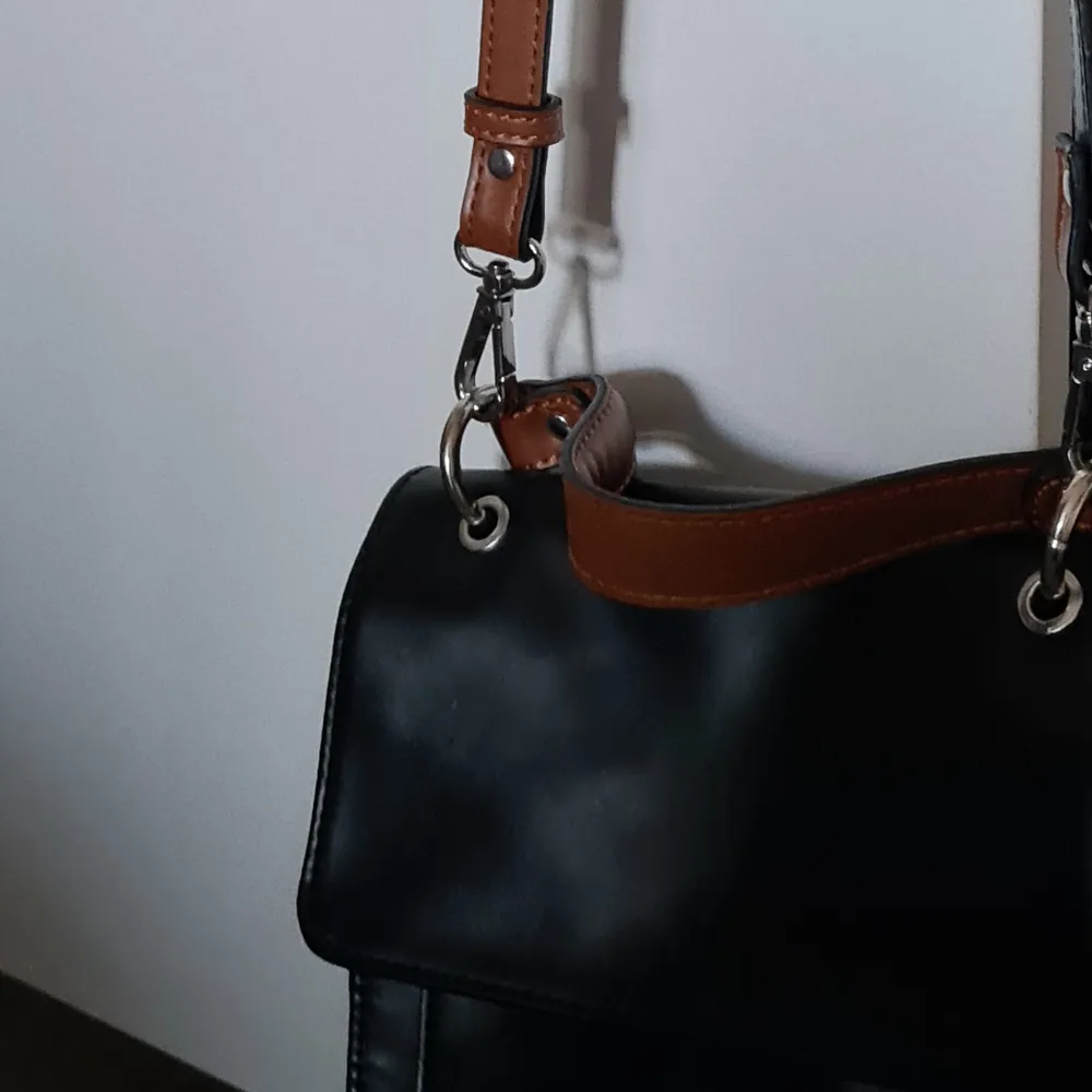 En liten svart väska i mycket gott skick med många fack! Går att ha som axelremsväska eller knäppa av remmen och ha som handväska.. Väskor.