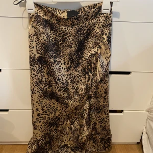 leopard kjol - En leopard kjol från ett danskt märke, i mycket bra skick och bara användt några fåtal gånger 🙌🏻 skulle säga att kjolen är i storlek XS, då den passar mig bra som har storlek XS 🤎 kjolen är omlott framtill 🤍 skicka för mer bilder och info!!