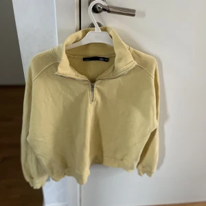 Gul långärmad  - En väl använd tjocktröja med krage + dragkedja i halsen. 