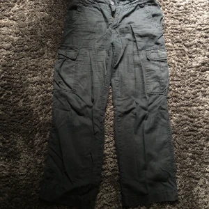Cargo byxor  - Ett par svarta cargo byxor det går att ändra storleken på byxan vid midjan. De är linne material på byxan. Vet tyvärr inte vart de är ifrån elr storleken då lappen klippt. Passar mig som är en 36a. Fler bilder kan skickas.
