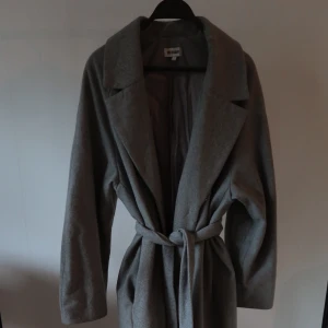 Kappa - Grå kappa från weekday. Inköpt för några år sedan. Använd, men i mycket bra skick. Bältet är avtagbart om man vill använda kappan mer oversized. Jag är 167 lång och kappan går ner till mina vader.