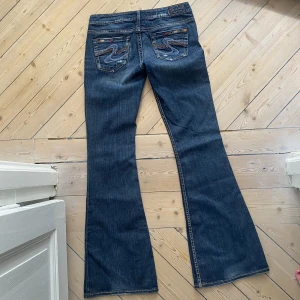 Lågmidjade jeans - Så snygga och unika lågmidjade jeans i bootcutmodell och mörk tvätt. Fina detaljer! perfekt skick. De är väldigt långa i benen, passar någon över 170❤️Skriv för mått/vid funderingar och kolla in mina andra jeans💗