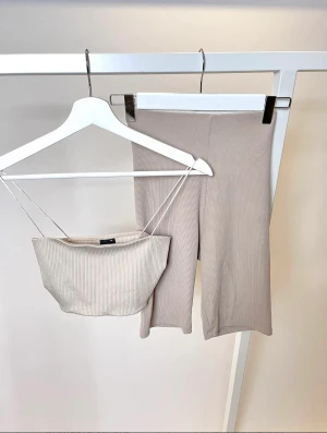 Ribbat set Gina Tricot strl. XS  - Fint ribbat beige set från Gina Tricot i fint skick. Topp strl XS. Byxor strl S  Material: 96 % Polyester, 4 % Elastan