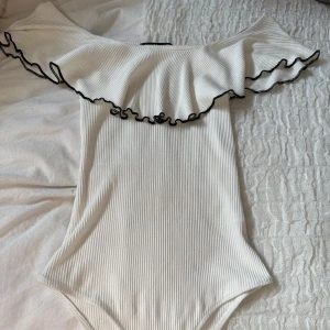 Off-shoulder body - En vit off-shoulder body från bershka. Ribbat material samt en volang.