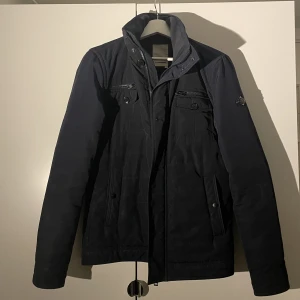 J Lindeberg jacka  - Fin höstjacka från J Lindeberg, använts några säsonger. Två knappar på framsidan av jackan är borta men det tänker man inte så mkt på, och om man skulle vilja sy dit några är det lätt gjort 