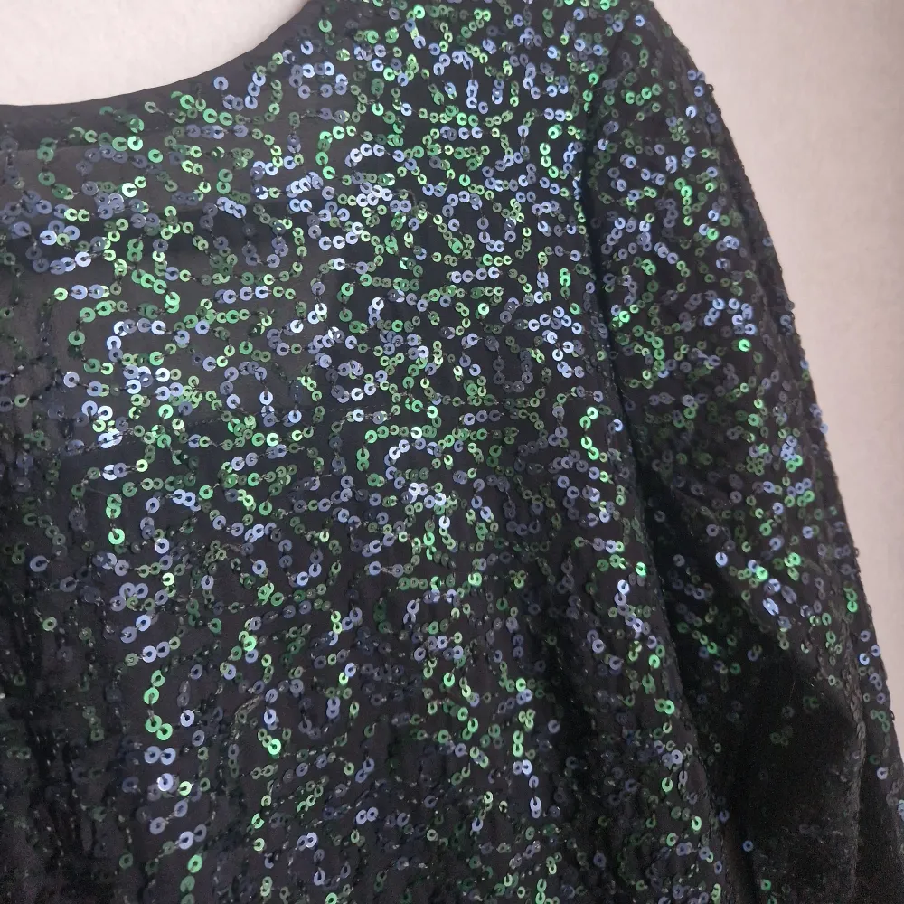 Superfin paljettklänning från H&M. Paljetter som går i blått och grönt. Öppning i ryggen. Använd vid ett tillfälle.. Klänningar.