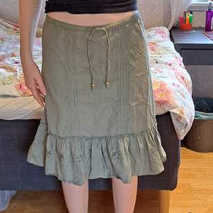 Super söt grön kjol som tyvärr är för liten för mig. Midi längd med knytning och volang. Se mått i bild 2. 