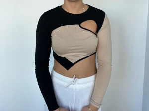 Svart/beige topp - Svart samt beige topp i cool design med öppet hål fram vid vänster sida. Köpt från Shein.