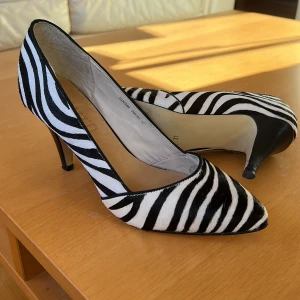 Zebrapumps - Pumps från Scorett med zebramönstrad tygklädsel. Klackhöjd 6cm. Använd ytterst sparsamt, nyskick. Strlk 37. Pris 150:-