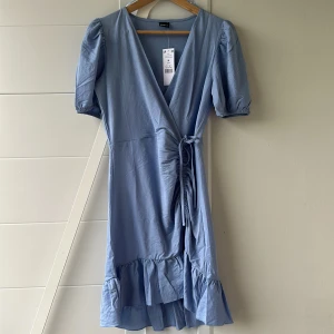 Sommarklänning Gina tricot - Blå sommarklänning i superbra skick då den är helt oanvänd och har kvar lappen på. Köpt på Gina tricot för några år sen. Den är i storlek M och längden på klänningen kan anpassas med snöret🩵
