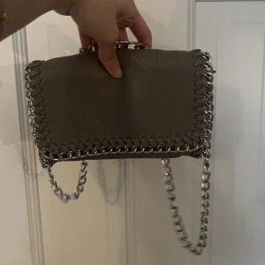 Tians väska - Den lilla verisonen av tiamo väskan. Bra skick men ena sidan har defekter (se bild 3) annars bra skick kan ha den undan band som en clutch och med band. 💞