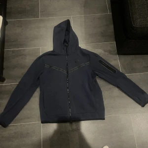 Nike tech flecce - Hej, jag säljer min tech flecce då jag inte andvänder den längre. Den har en liten fläck bak på tröjan men det är inget man tänker på. Har andvänts några gånger. Köpt på JD sports i Gbg. Ny pris 1250 kr.