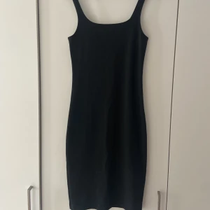 Svart tajt klänning  - Jättefin, stilren tajt klänning med en lite slit bak. Är tyvärr för tajt för mig. Går precis över knäna på mig som är 175cm. Aldrig använd, bara provad. Inte inte alls genomskinlig. Nypris 400kr.