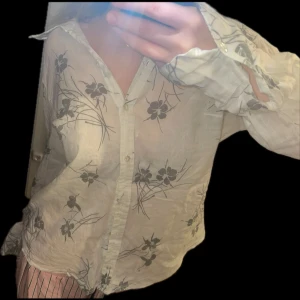 Luftig vit skjorta med grått blomster mönster  - Den här skjortan är i perfekt skick och har alla knapparna kvar och även lapparna på insidan är kvar, den är väldigt luftig och är lite genom skelning, och den ända anledningen att jag säljer den är för att jag måste tända ur garderoben 