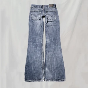Levisjeans - Midja:74 innerben:80 Vintage Levis, lågmidjade bootcut. Uppskattar passa en XS. Lite smånötta, nötningar vid fotändar samt lite blekta partier. Svagare fläck ena ben enligt bild. Överlag bra skick!🤍