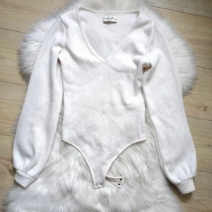 Krämvit bodysuit med långa puffiga ärmar, v ringad, stickad - Bra skick! Aldrig använt