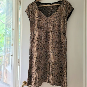 Klänning brun/beige stl.M - Superfin klänning/ tunika viskos stl.49 men är sm en 38 Medium. Beige/brun m svart spetskant. Snodd i midjan.  Begagnad, fin, inga fel!
