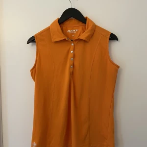 Topp träningsmaterial - En orange pikétopp i träningsmaterial. Storlek XL men känns snarare som M-L