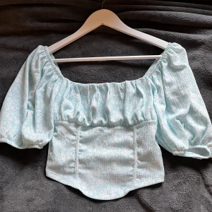 Fin topp från Gina - Använd 1-2 gånger, är som ny. Cropad och går ner lite på magen. Man kan ta ner ärmarna så den blir off shoulder. 