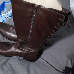 Höga Skinnstövlar bruna snörade - Använda 4-5 ggr  skinntövlar i nyskick, förvarade med stöd. Spetsig klack.