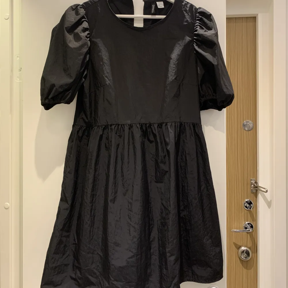 Kort svart klänning med lite puffärmar, tightare i ”överdelen” sen är den lite mer ”puffig” men inte så puffig i underdelen. Lite tunnare i materialet. . Klänningar.