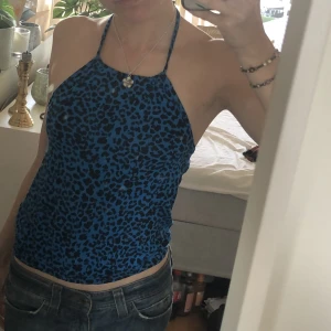 Blå festlig halternecktopp💘 - Säljer denna blåa halternecktoppen med svart leopard mönster från bikbok💘 storlek xs och knappt använd😁OBS: det vita fläckarna som syns på bild ett är på spegeln och inte på plagget!!💕