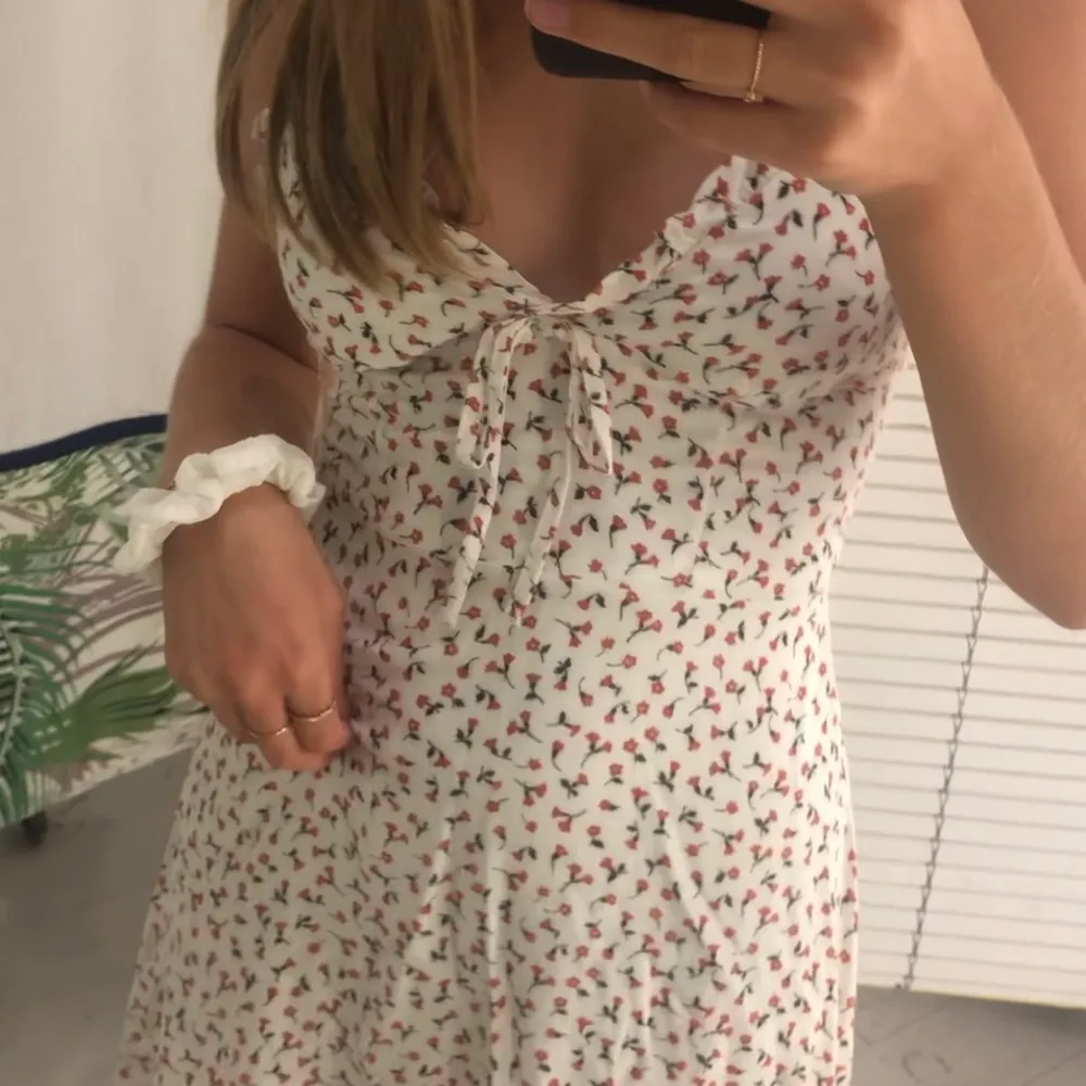 En klänning söt som socker😍, perfekt till sommaren och använd vid endast ett tillfälle, alltså är den som ny! Klänningen är vit med röda blommor i storlek xs. Mekot.