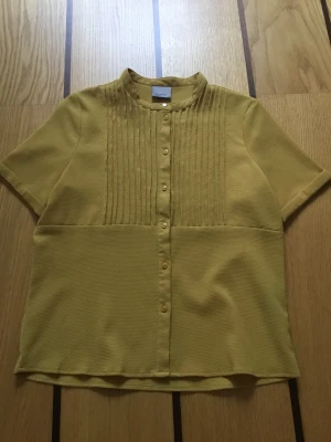 Senapsgul blus XS - Senapsgul blus från Vero Moda i storlek XS. Axelbredd: 37 cm, Längd: 58 cm. 97% polyester, 3% elastane. Mycket bra skick!