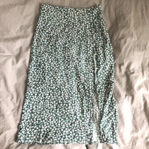 Grön midiskirt  - Fin grön midiskirt med vit blommor och en slits