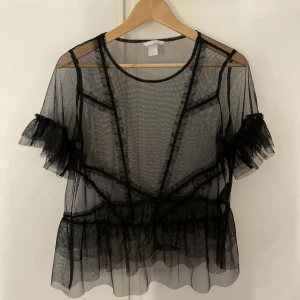 Topp från H&M - En svart genomskinlig T-shirt från H&M i storlek S, funkar också som M. Fint att styla med en svart bh under eller ett svart linne. 