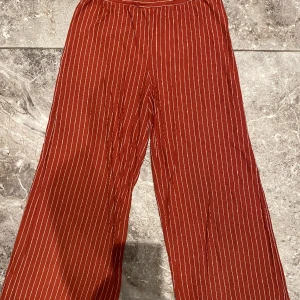 Byxor 134/140 - Randiga röda byxor. Säljer pga stor garderobrensning. Kika gärna på mina andra annonser, säljer mycket. Samfraktar gärna:) 