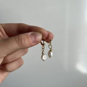 Örhänge - Guldigt örhänge i rostfritt material med äkta sötvattenpärla!