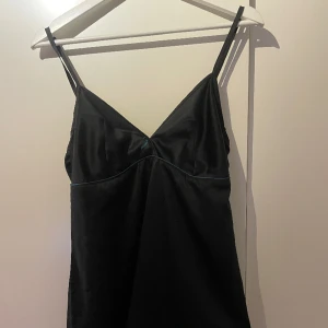 Slipdress - Svart slipdress, kort. Köpt på Humana, grön/blå rosett. Skriv för fler bilder, pris går att diskutera!