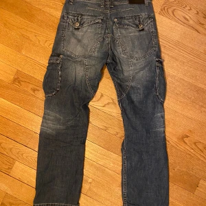 Jeans cargofickor - Jeans med snygga cargofickor och metalldetaljer.  Storlek 152, passar nog personer upp till 160cm långa.
