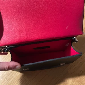 Svart väska  - Svart liten skinnväska som är röd innuti 🥰 Bandet kan vara crossbody och lite kortare. 