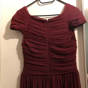 Säljer denna vinröda klänning, från NLY eve, använd enbart en gång. Är i gott skick, maxiklänning, och som ni ser på bilderna har den omlott design framtill och baktill. Har dragkedja baktill. Är utan ärmar. 